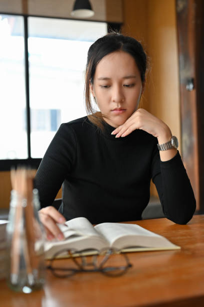 istock Female college student focused and concentrated reading a textbook 1406628955