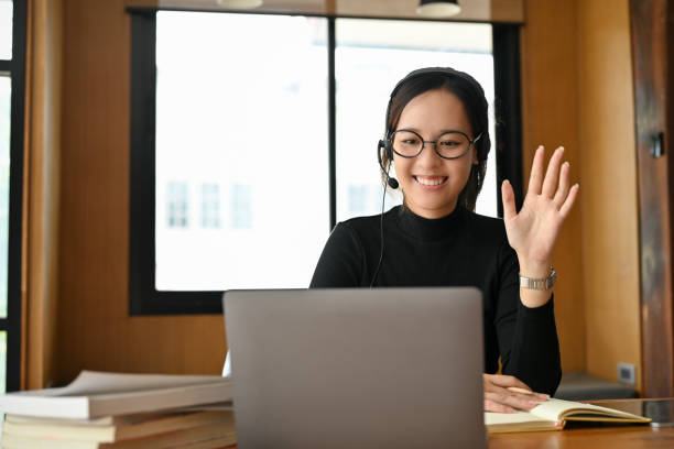 Cheerful young asian female online tutor or teacher teaching her students on online Cheerful and professional young asian female online tutor or teacher teaching her students on online via laptop computer. E-learning concept online tutors stock pictures, royalty-free photos & images
