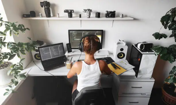 Photo of Girl programmer in the modern developer workplace for writing code with white computer desktop and comfy armchair.
