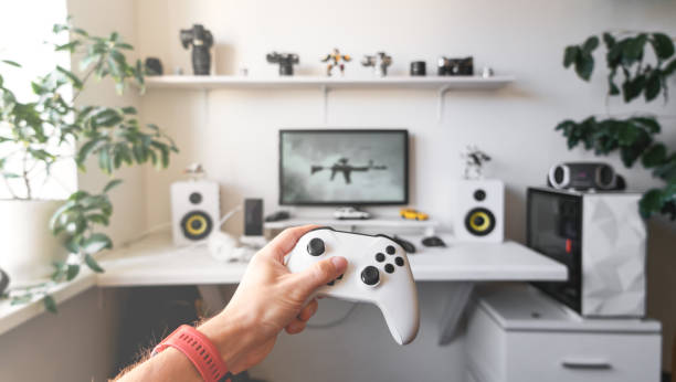 zbliżenie męskich rąk trzymających biały bezprzewodowy gamepad na białym biurku komputerowym. - gaming systems zdjęcia i obrazy z banku zdjęć