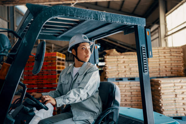 Mid adult female driving a forklift in a warehouse stock photo