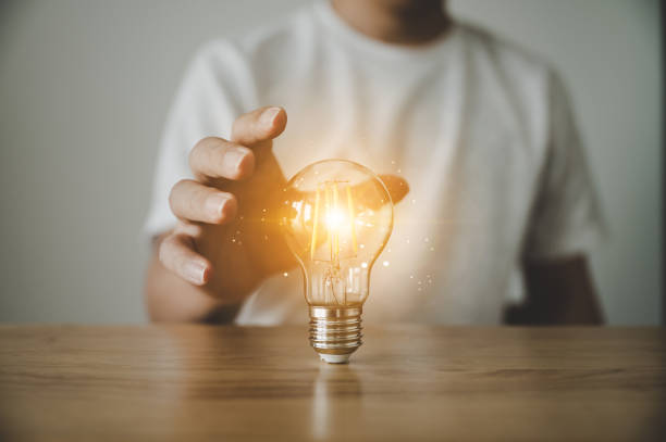 istock Hand holding light bulb on wood table. Concept of inspiration creative idea thinking and future technology innovation 1406635852