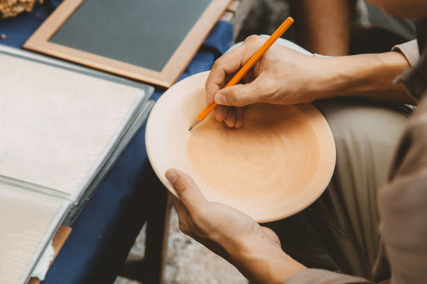 istock Artist paint sketch drawing Sukhothai traditional style pattern on dish earthenware, making of handcraft pottery in Sukhothai, Thailand. 1406639112