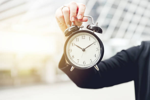istock closeup hand holding alarm clock for working time aware or realize in lifestyle 1406639197