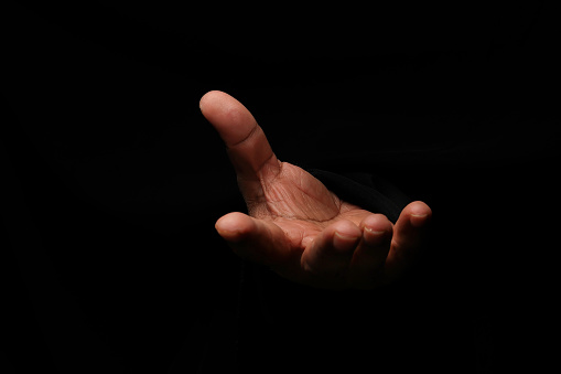 Asian male dark skinned single hand fist finger on black background palm up