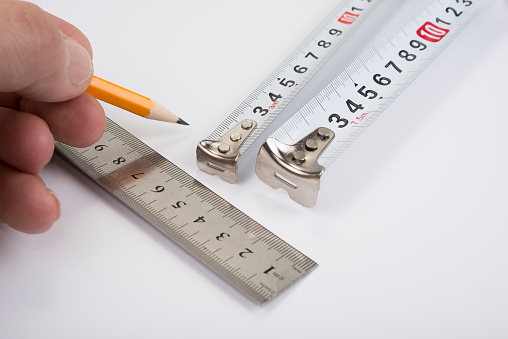 Steel ruler and tape meter with wood pencil on white
