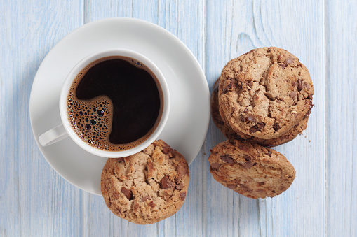 Chocolate chip cookies and cup of coffee on blue wooden background or table, top view