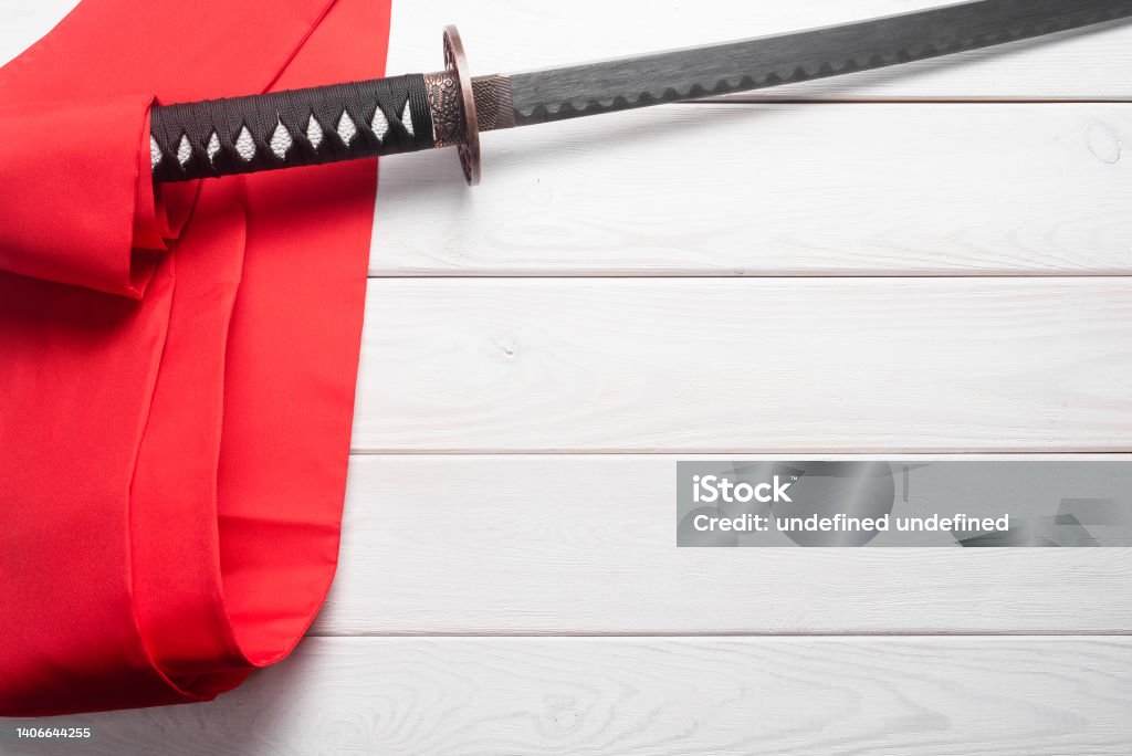 Katana. Katana sword and red waist band on the white table flat lay background with copy space. Backgrounds Stock Photo