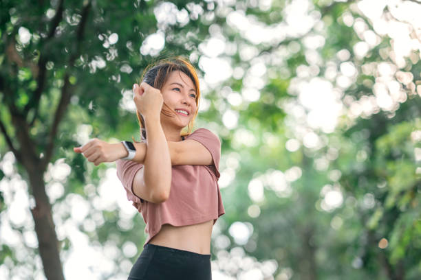 Fitness woman doing stretch exercise stretching her arms, female stretching for warming up before running or working out in the park outdoor. stock photo