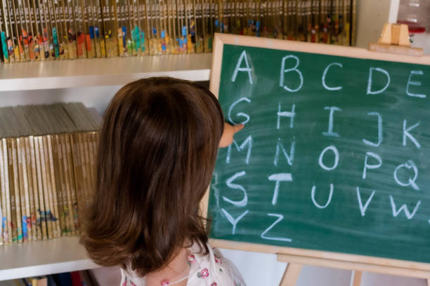 il bambino indica la lettera "g" sulla lavagna (lavagna). - teaching blackboard preschool alphabetical order foto e immagini stock