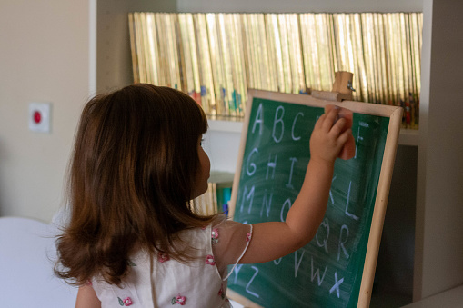 The child has completed spelling for today and now she is ready for new words and letters. She uses a cleaning sponge to wipe the letters off the board.