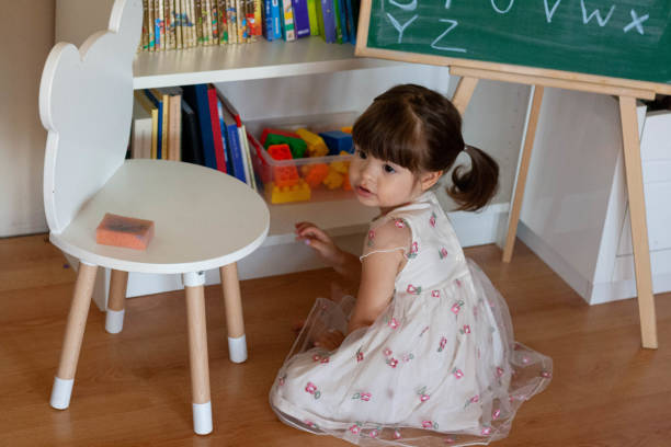 una ragazza si siede sul pavimento e pensa a quale libro prendere dopo. - teaching blackboard preschool alphabetical order foto e immagini stock