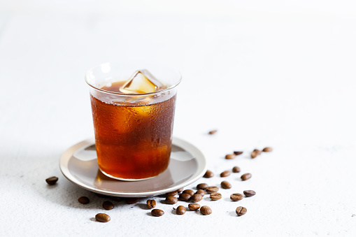 Glass of iced coffee, Iced Americano coffee, with coffee beans on white marble table.