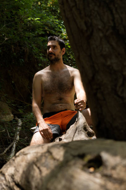 istock young man in swimsuit sitting in a tree by the river 1406654242