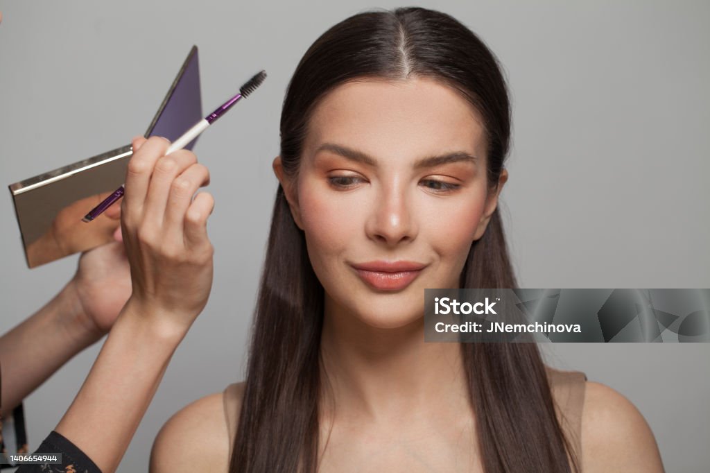 Beautiful female model face closeup and makeup artist hands with brush and eye shadow palette Make-Up Artist Stock Photo