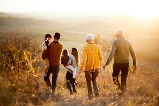 istock Back view of multi-generation family moving down the hill at sunset. 1406656352
