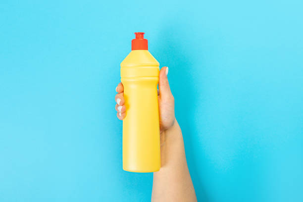 istock Housewife's hand holds a spray with cleaning agent on a blue background. Detergent for various surfaces in the kitchen, bathroom and other rooms. Close-up. Light pastel blue background. 1406656886