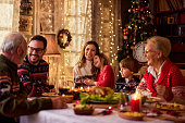 Cheerful extended family talking during Christmas dinner at home.