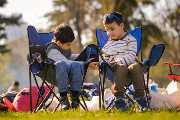 istock Two little boys sitting in camp chairs at campsite 1406658391