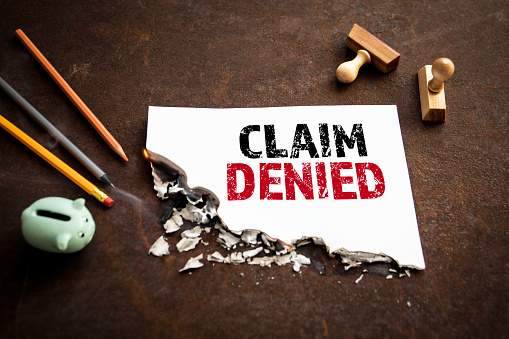 CLAIM DENIED. Text on a burning piece of paper.