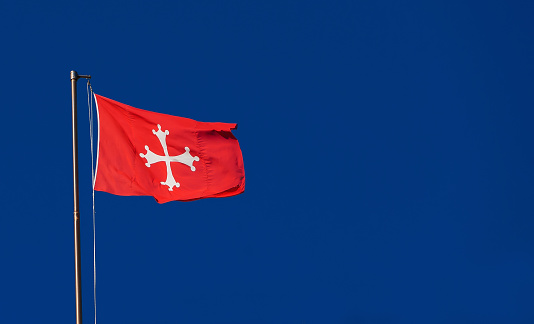 Republic of Pisa old red flag with white cross waving in the wind. One of the most powerful ancient Maritime Republic in the Mediterranean Sea during the Middle Ages
