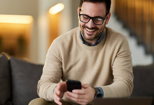 istock Happy man text messaging on cell phone at home. 1406659518
