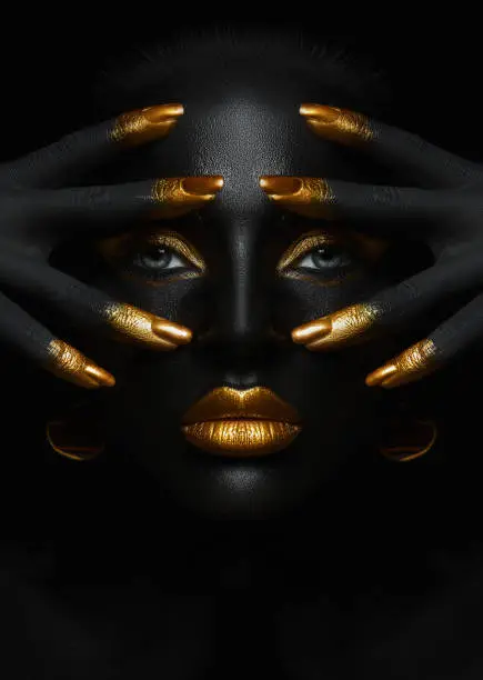 Photo of Beauty woman black skin color body art, gold makeup lips eyelids, fingertips nails in gold color paint. Professional gold makeup