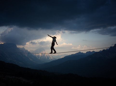 Man criossing highline in steady ballance in beautiful mountain landscape at sunset
