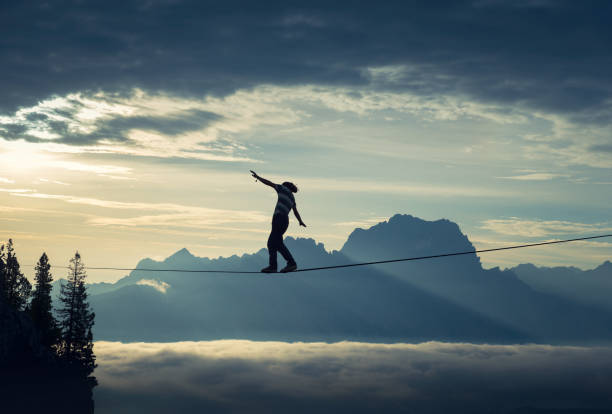 Keeping balance Man walking on highline and keeping a steady balance in beautiful mountain landscape tightrope stock pictures, royalty-free photos & images
