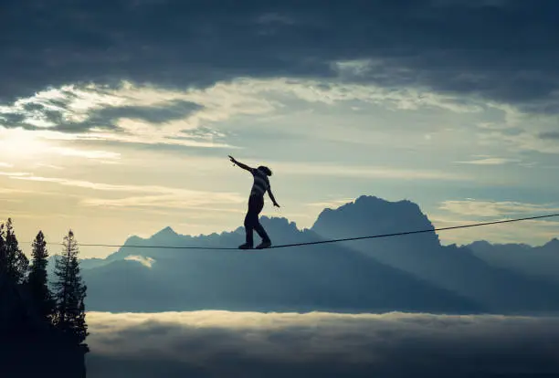 Man walking on highline and keeping a steady balance in beautiful mountain landscape