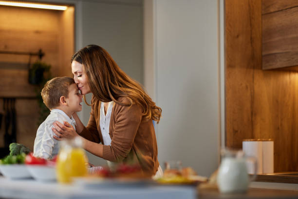 istock Loving single mother kissing her son in the kitchen. 1406660476