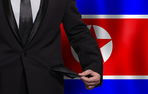 North Korea flag background with man showing empty pockets. Financial difficulties, bad economy, no money and social problems in North Korea concept.