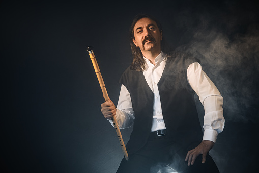 Turkish musician and reed flute with black background and fogs