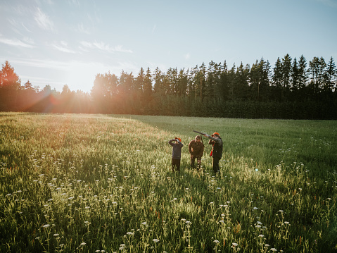 Drone view of father and two sons, hunting on a meadow. South of Estonia.