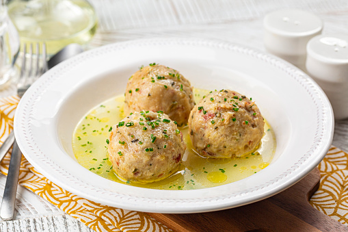 Canederli or Knödel in broth with green onion, typical pasta or dumplings for Alps, Alto Adige, German, Italian, Austrian cuisine. Made from stale bread, milk, eggs, speck.