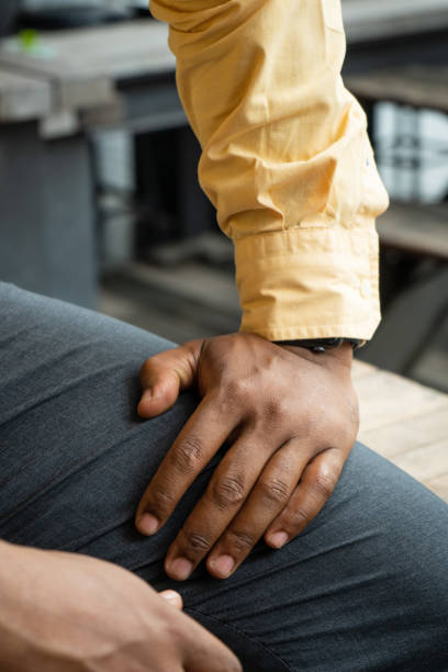 African American Businessman Resting Hand on Thigh An African American businessman resting his hand on his thigh at a cafe in Chiang Mai, Thailand. hand thigh stock pictures, royalty-free photos & images