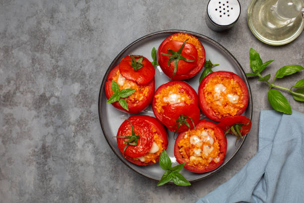Baked stuffed tomatoes with rice and cheese. Top view. Grey table, copy space. stock photo