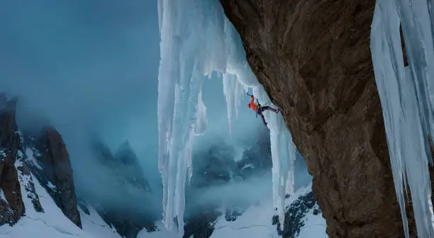 Man climbing a extreme dangerous ice face in surreal mountain  scenery