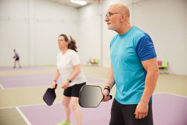 los adultos mayores están jugando pickleball. - racket ball indoors competition fotografías e imágenes de stock