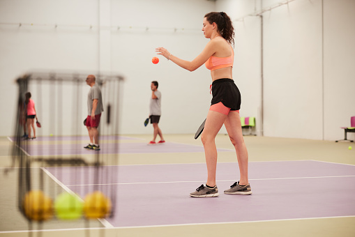 A young woman is serving in pickleball training.