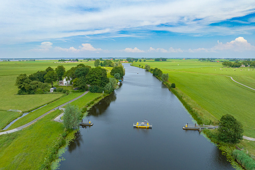 Beautiful characteristic polder landscape with the reflections of the blue sky with clouds in a wide ditch, on the border of the city of Schiedam, near Rotterdam, the Netherlands