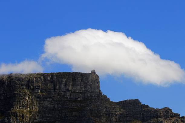 Authentic colors of dusk in the sky over the famous landmark of Table Mountain, Cape Town, as seen from the beach at Bloubergstrand to the north of the city. The waves coming in from the sea have been softened by a long exposure.