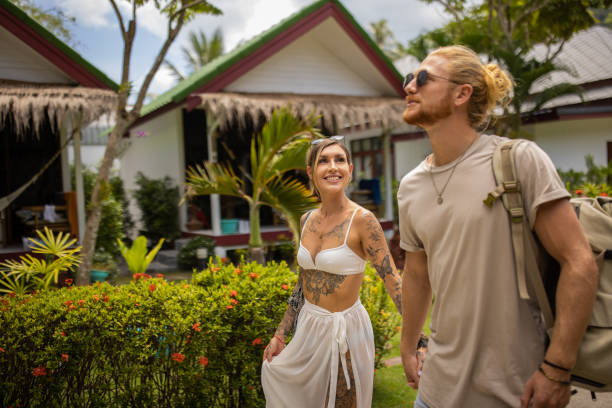 Caucasian couple holding hands, while walking through tourist resort Young Caucasian couple holding hands, while walking through tourist resort during their vacation tourist couple candid travel stock pictures, royalty-free photos & images