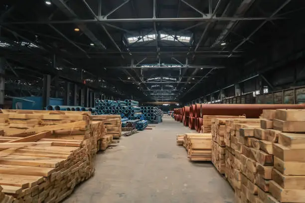 Photo of Large warehouse with water pipes and stacks of wood in factory