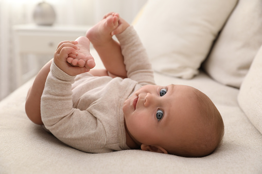 Adorable little baby lying on sofa at home