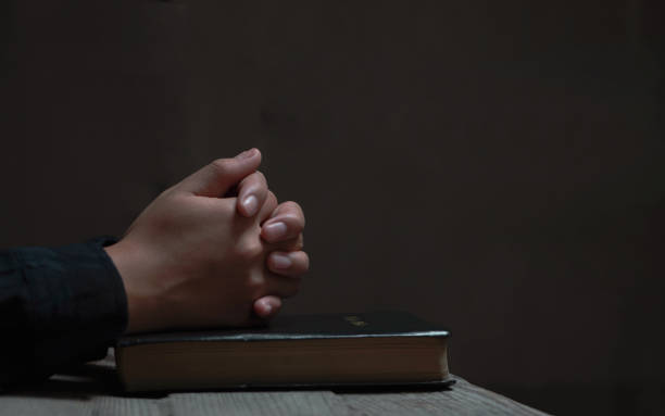 de cerca las mujeres cristianas leen la biblia. manos cruzadas en oración sobre una santa biblia sobre mesa de madera. - praying human hand worshipper wood fotografías e imágenes de stock