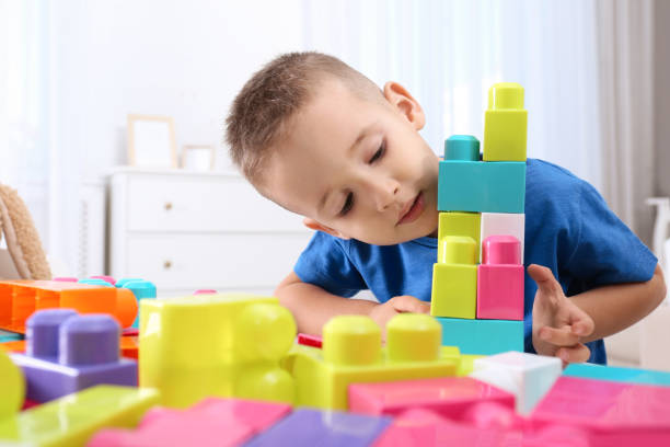 istock Cute little boy playing with colorful building blocks at table in room 1406680084