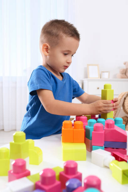 istock Cute little boy playing with colorful building blocks at table in room 1406680159