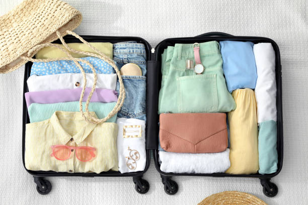 istock Open suitcase packed for trip and accessories on white blanket, flat lay 1406680872