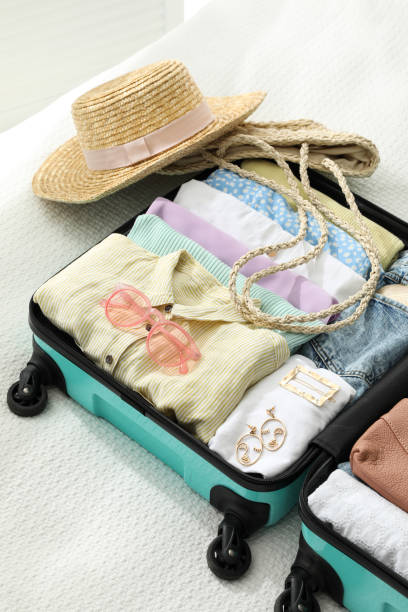 istock Open suitcase packed for trip and accessories on bed 1406680876